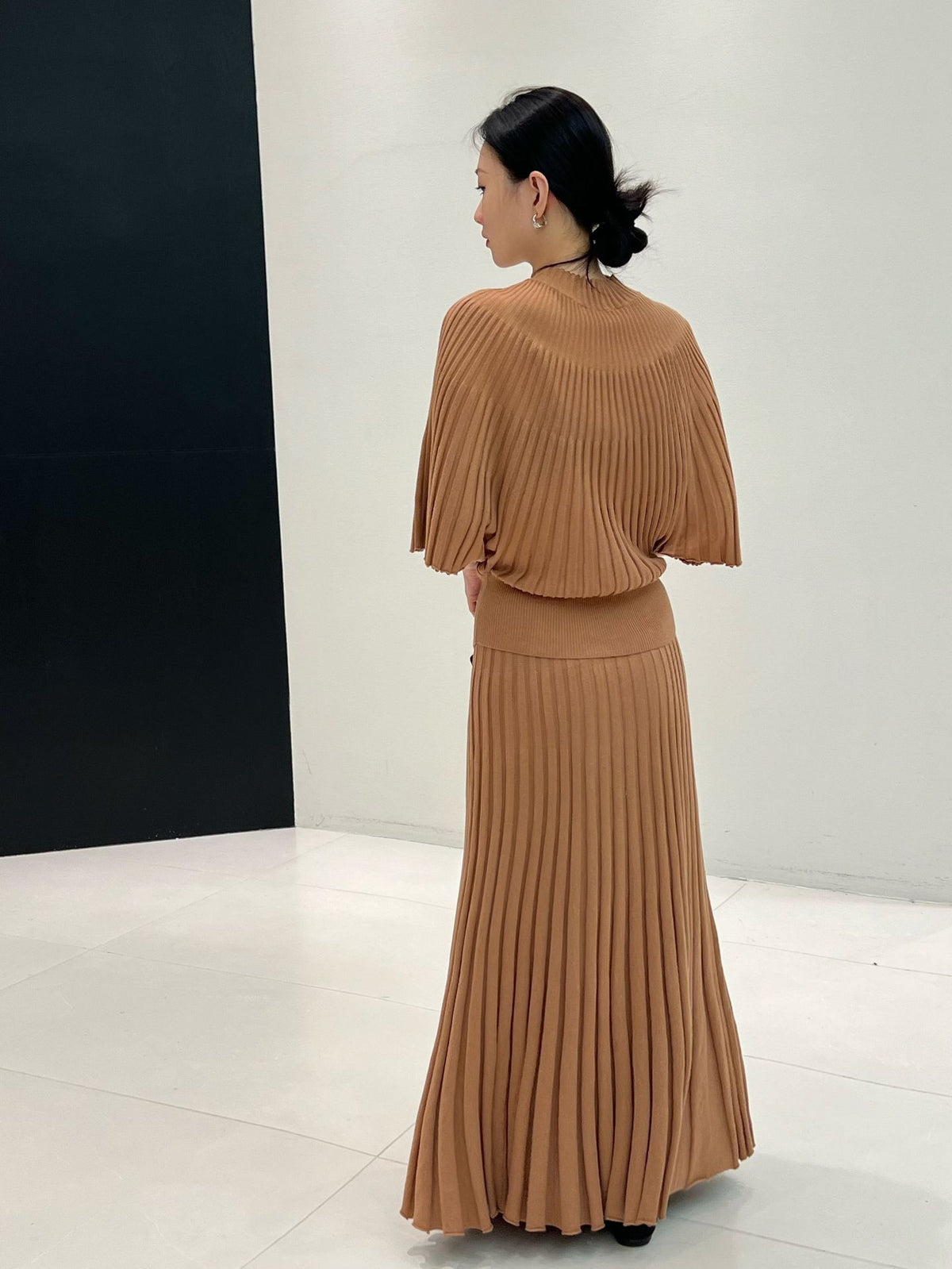 Back view of a caramel long ribbed knit skirt with flared hem styled with a knit top, top not included