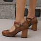 Brown brogue Mary Jane pump with a buckled cross strap and wood grain block heel, worn on a concrete floor
