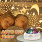 Rotating star projector casting colored stars and a moon across a dark ceiling