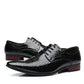 Pair of black crocodile embossed pointed toe derby dress shoes with a red brown heel, side view on white