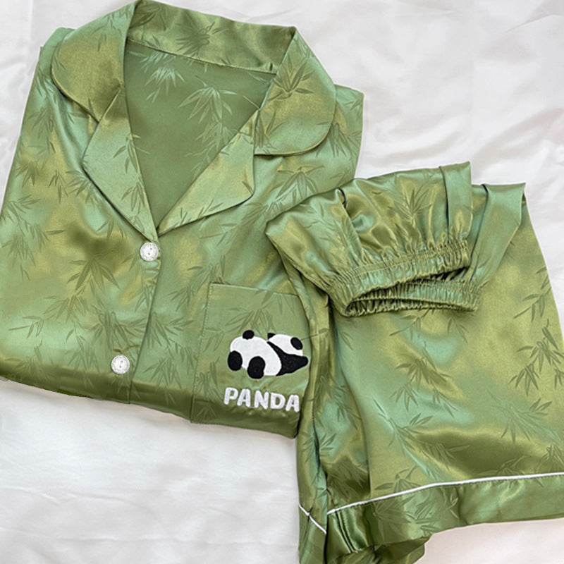 Moss green ice silk pajama set folded on a white bed with a panda chest pocket and elastic waist shorts