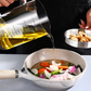 Oil poured from the graduated glass jug into a frying pan of vegetables on a worktop