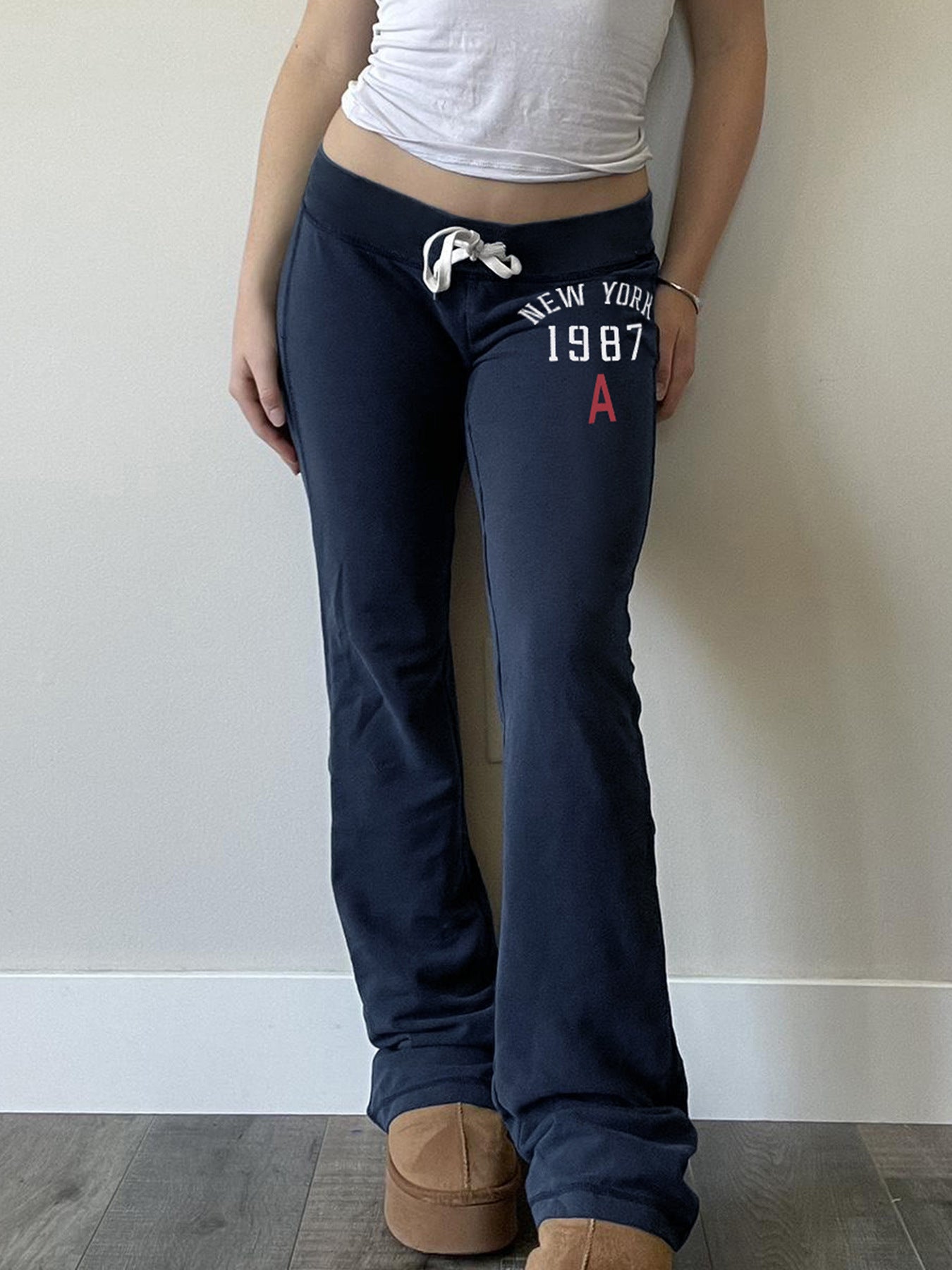 Navy low-rise flared drawstring sweatpants with a white New York 1987 print worn front view