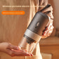 Gray electric coffee grinder held in both hands, one-button body, knurled ring and clear grounds chamber