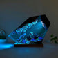 Submarine themed resin night light glowing blue in a dark room on wood base