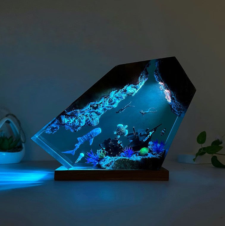 Submarine themed resin night light glowing blue in a dark room on wood base