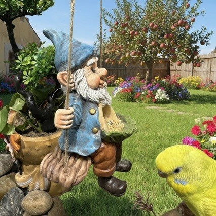 Resin gnome bird feeder hanging in a garden with a budgie perched nearby