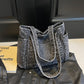Washed dark brown denim shoulder tote on a leather jacket, medium structured body with end patch pockets