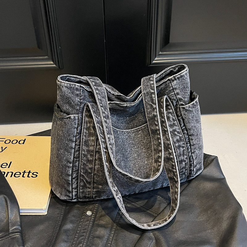 Washed dark brown denim shoulder tote on a leather jacket, medium structured body with end patch pockets