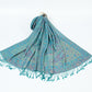 Teal green paisley shawl with a gold border and teal tassels spread on a white background