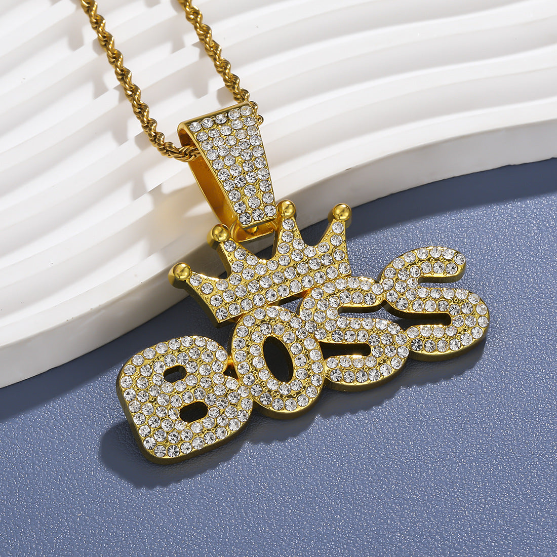 Crown pendant necklace in gold tone under soft studio light
