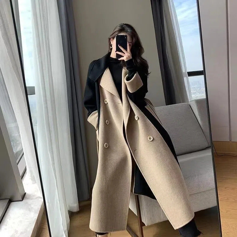 Long black overcoat with camel collar and cuffs worn open over black jeans