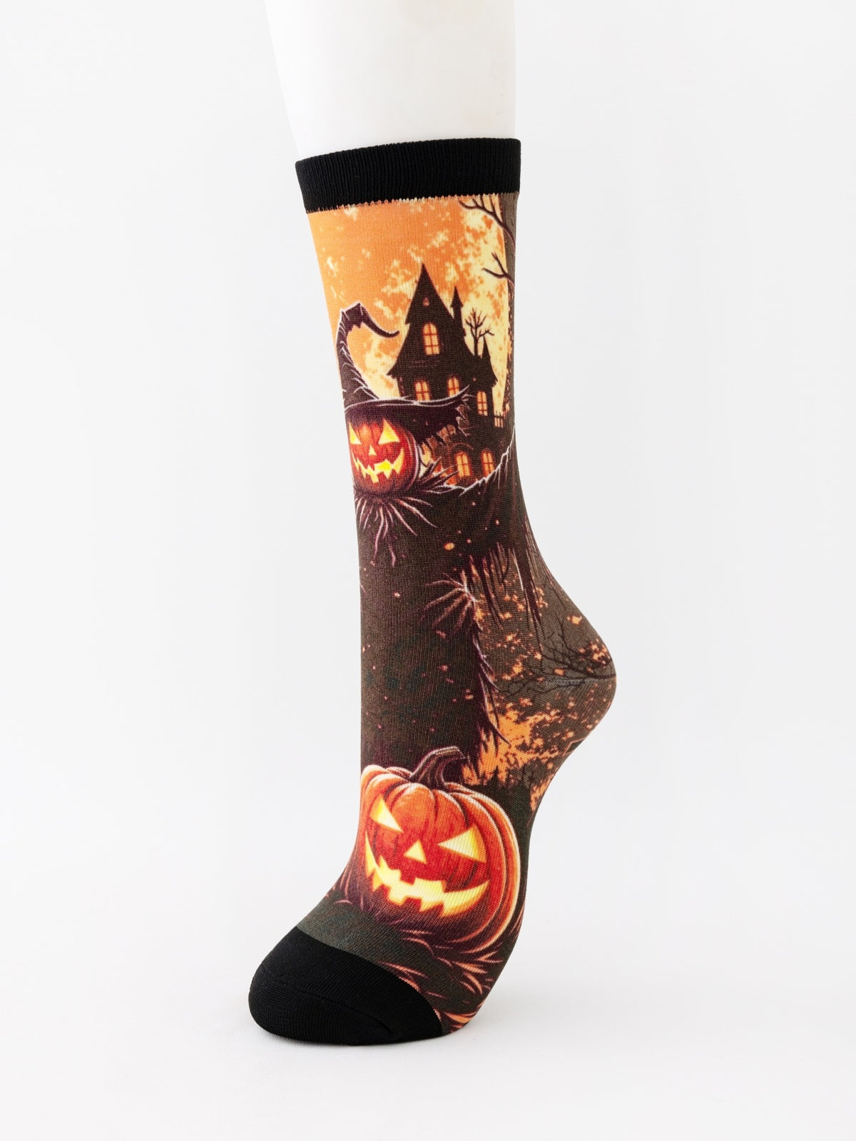 Mid-calf sock on a mannequin printed with an orange haunted house on a hill and a grinning pumpkin