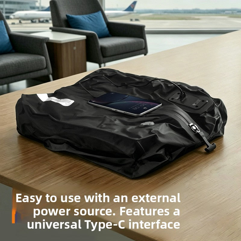 Black compression bag compressed flat on a lounge table with a phone and cable connected to its pump