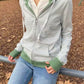 Green striped zip-up hoodie with kangaroo pocket and ribbed green hem and cuffs, worn with jeans