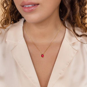 Model wearing a gold plated necklace with a red teardrop stone on a fine chain