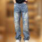Man in blue ripped straight leg jeans with a hand in the pocket, black tee and white sneakers