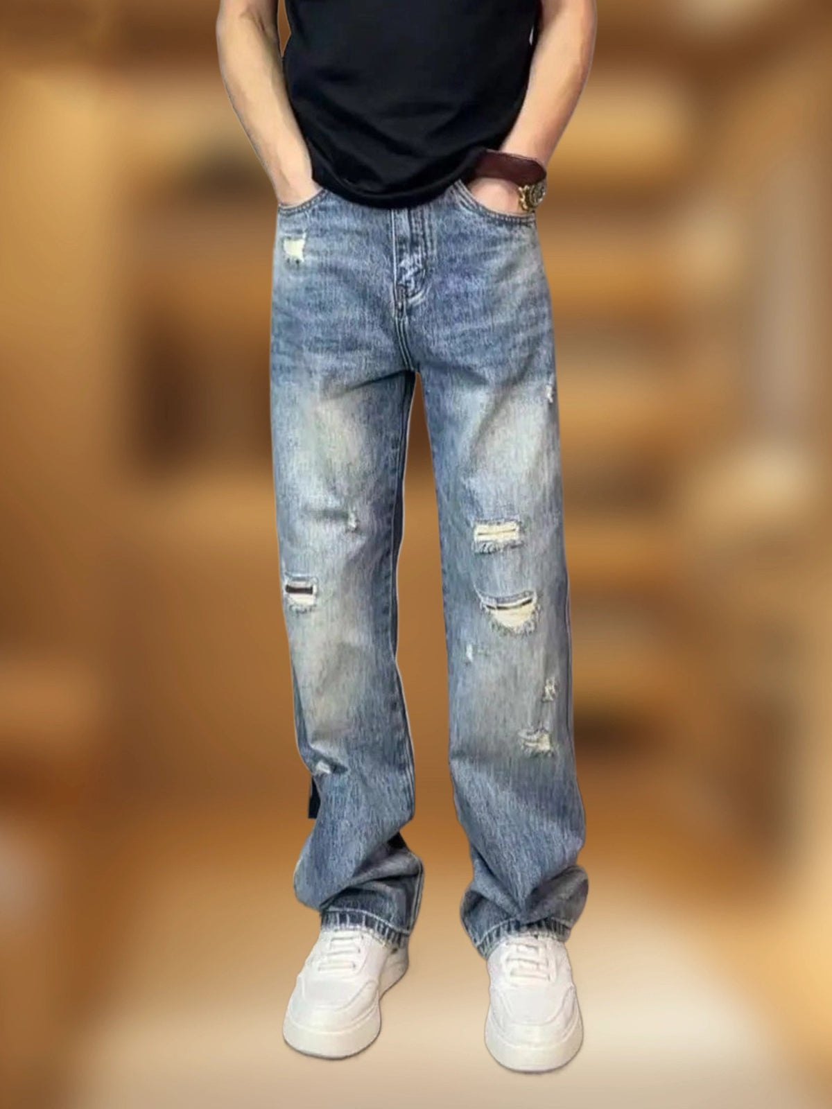 Man in blue ripped straight leg jeans with a hand in the pocket, black tee and white sneakers