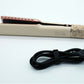 Hair straightener side view with rating label and coiled black power cord
