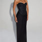 Woman in a black strapless long dress with a sequin bodice and draped skirt on a grey background