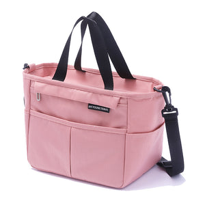 Pink insulated lunch bag with twin top handles and a detachable adjustable shoulder strap clipped on