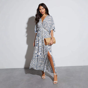 Ivory and cobalt paisley print maxi dress worn walking with a straw clutch, White blue colourway