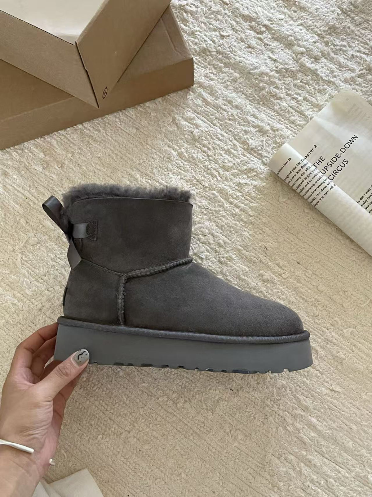 Gray suede platform ankle boot with a back bow held in a hand, Gray Thick Sole option, size 35