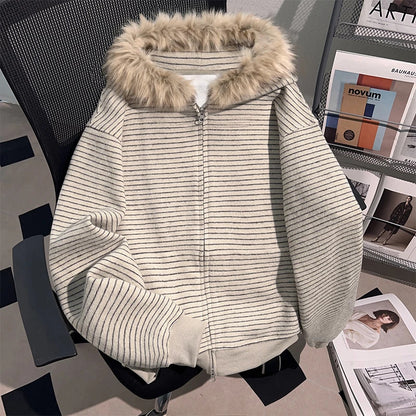 Cream striped hooded zip cardigan with a tan vegan fur trim on the hood, front view on a chair
