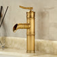 Tall antique copper bamboo basin faucet with an open waterfall spout against a marble wall