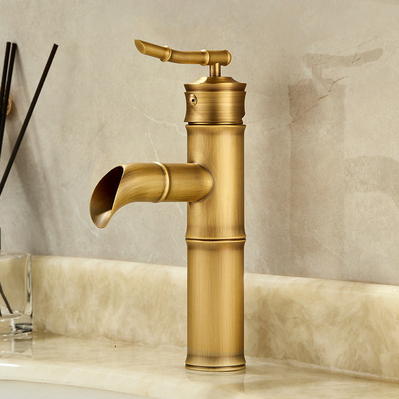 Tall antique copper bamboo basin faucet with an open waterfall spout against a marble wall