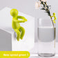 Sprout green figure seated on a white block, with a small figure on a glass of water holding a flower stem