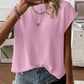 Woman wearing a solid color round neck cap sleeve knit top with a relaxed drape over denim shorts