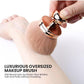 Oversized mushroom makeup brush buffing across a forearm to show softness