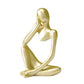 Gold abstract resin meditator figurine in a seated thinking pose on a plain white background