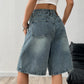 Side profile of the denim wide-leg shorts showing the wide hem and topstitched seam