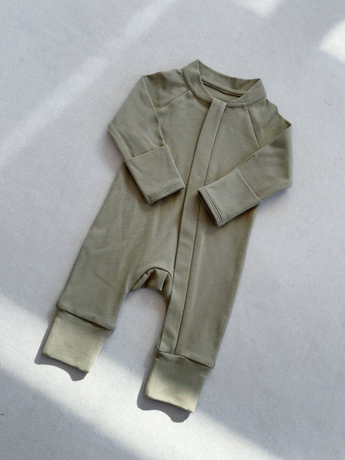 Olive Green zip front baby romper laid flat on a gray floor, image of the 90 cm, 18 to 24 months size option