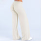 Back view of ivory wide leg pants with a fold over waistband and white sneakers on a pale blue background