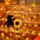 Orange glowing spider web net light with a black spider prop on a wood floor