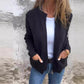 Black zip-front cardigan with round neck and patch pockets, worn over a white top and jeans