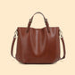 Chestnut brown leather bucket tote with top handles and a detachable shoulder strap on a cream background