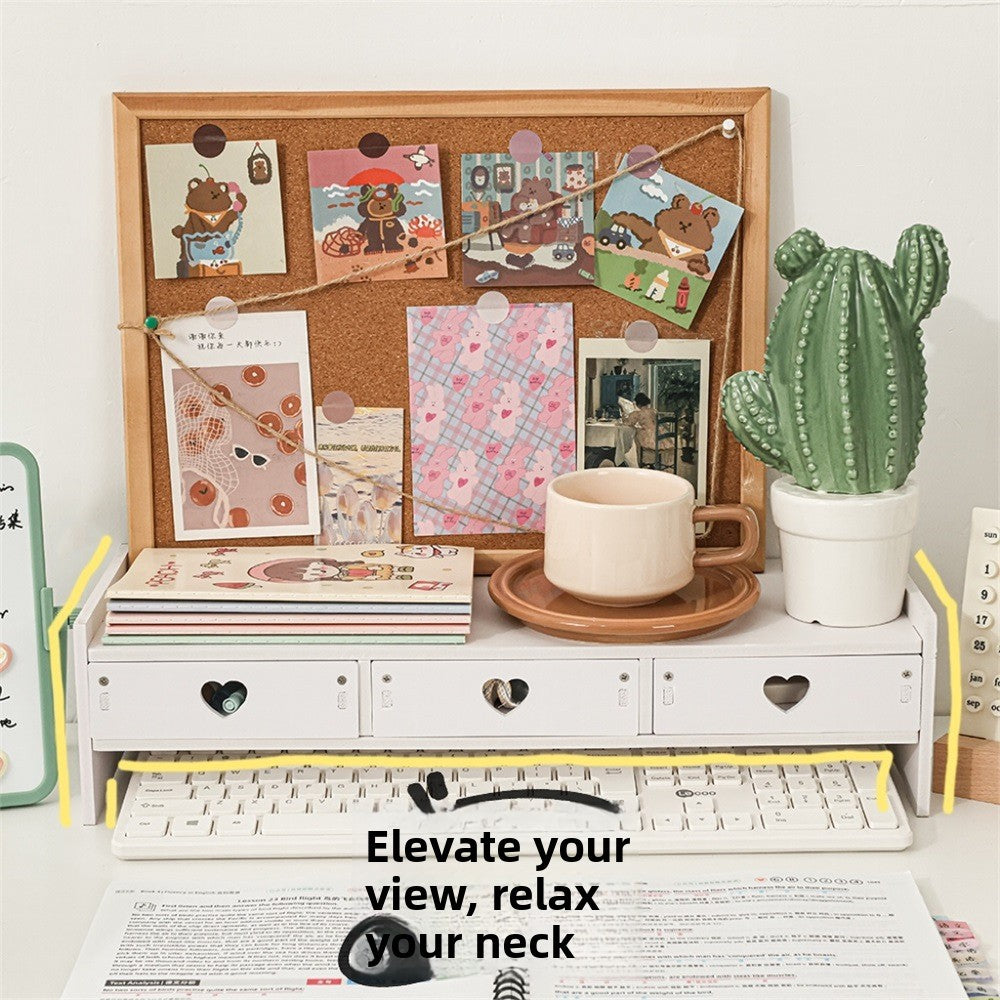 White desktop rack with three heart cutout drawers above a keyboard, with books, a mug and a plant on top