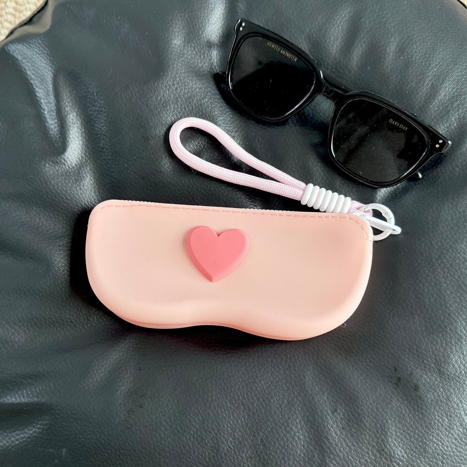 Silicone sunglasses case with a zip around the top and a braided wrist lanyard on a clip