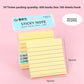 Pink lined sticky note pad on a desk beside a pen and a planner