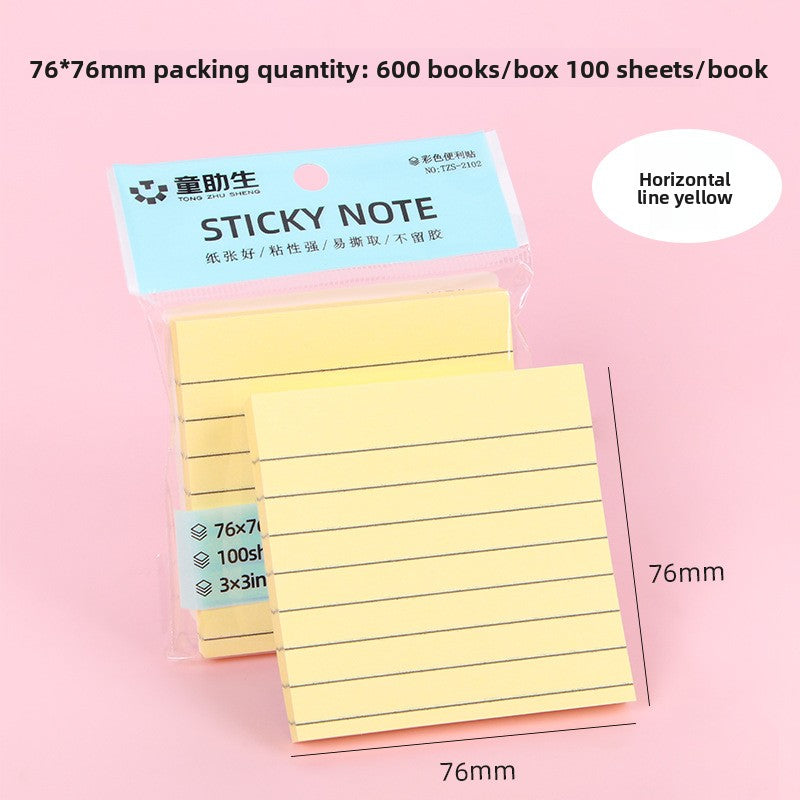 Pink lined sticky note pad on a desk beside a pen and a planner