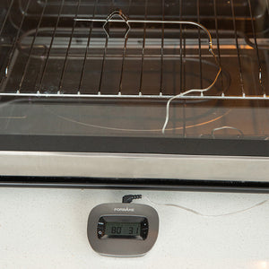 Thermometer probe inside an oven with the display unit reading on the counter below