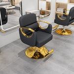 Black salon styling chair with curved gold metal armrests on a gold disc base in a salon