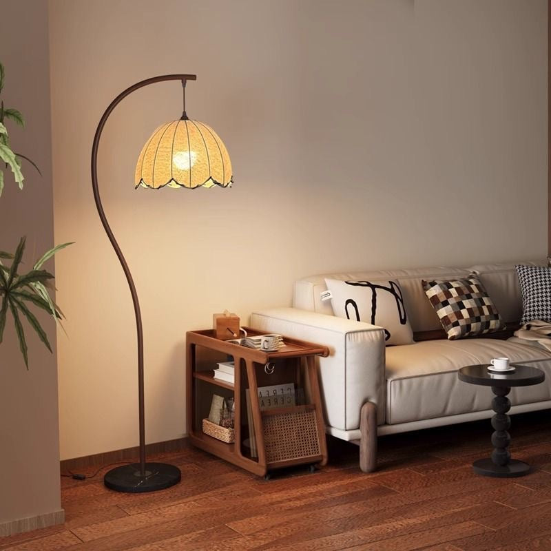 Arc lotus leaf floor lamp glowing warm beside a sofa in a living room corner
