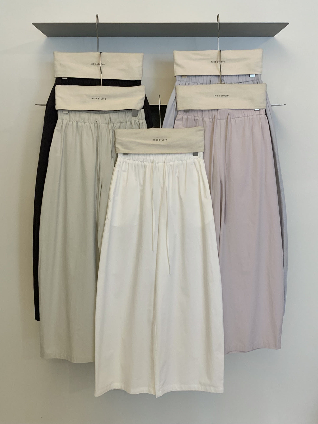 Cotton wide leg trousers grouped on hangers in cream, lilac and carbon ash