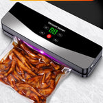 Space gray cordless vacuum sealer sealing a filled bag of marinated food with the indicator light glowing along the bar