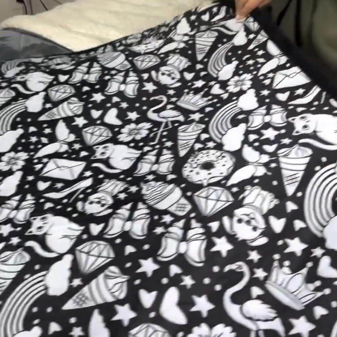 Kids coloring blanket held open showing black and white outline scene of animals and flowers